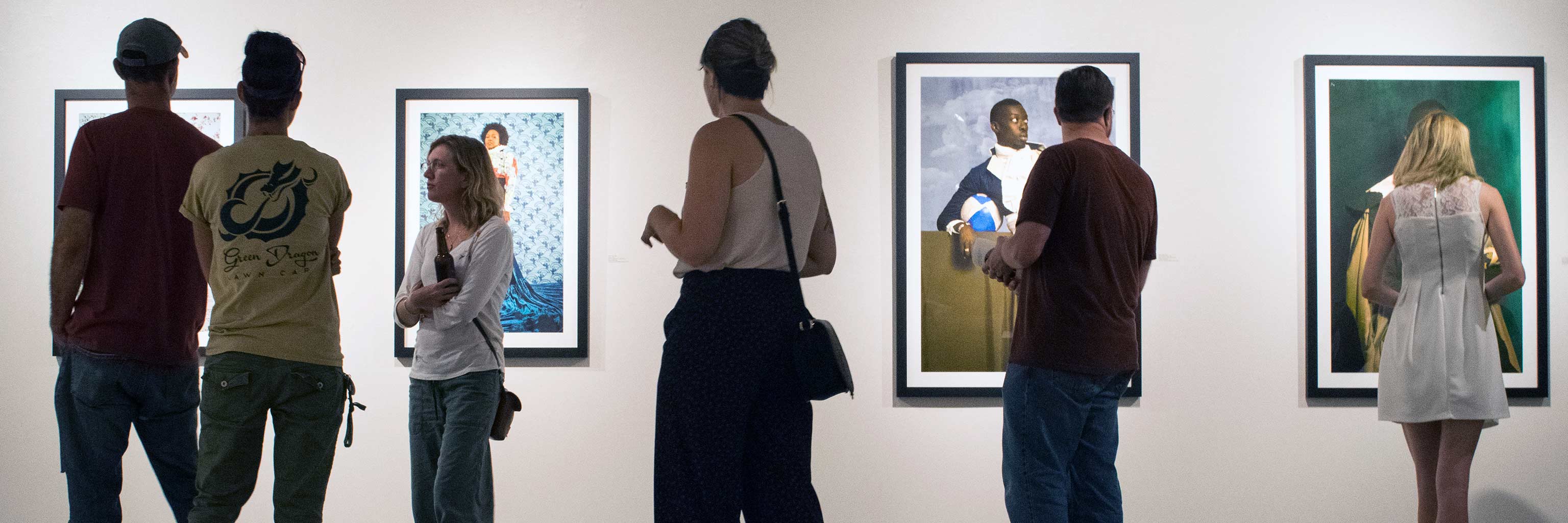 people looking at paintings in an art gallery