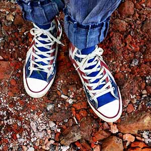 red, white and blue sneakers on a dirt surface